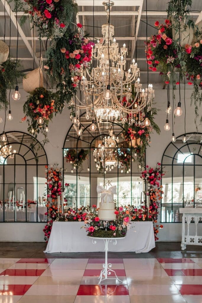 Pink wedding decor shown in hanging floral displays and pink and white checkered flooring