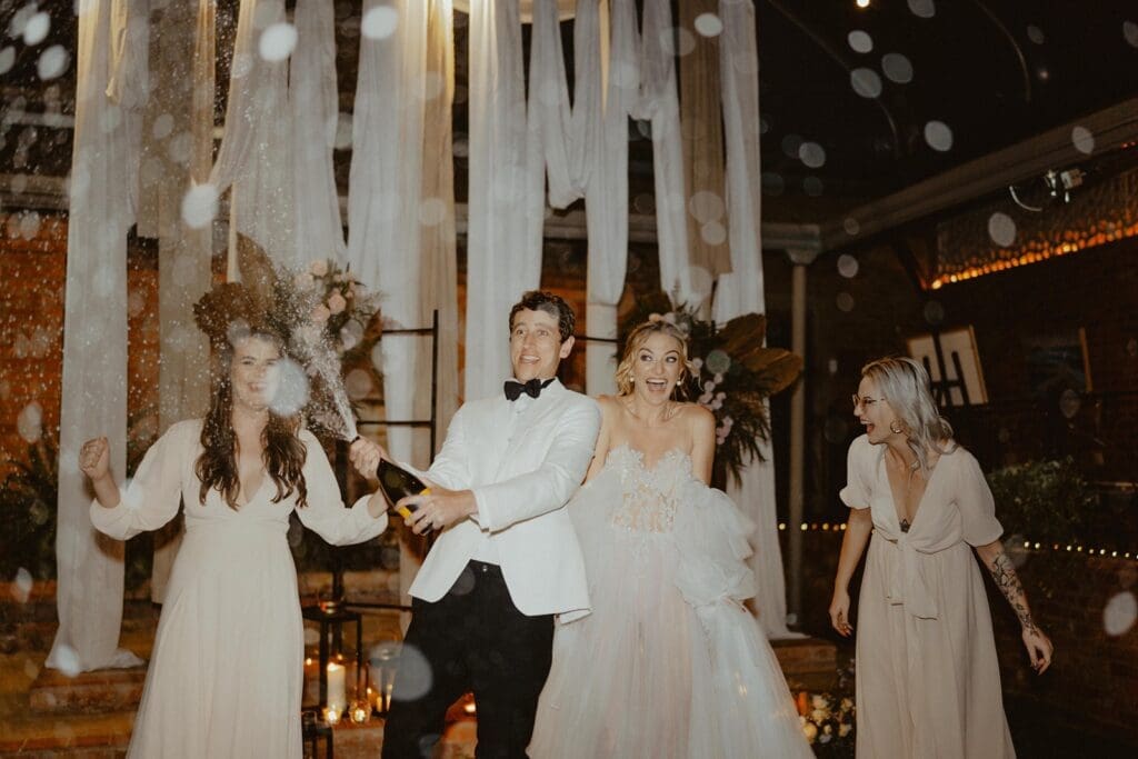 Small bridal party popping champagne