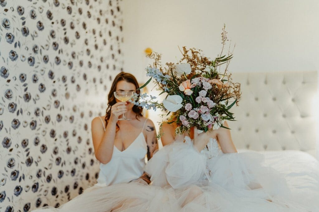 Bride and bridesmaid sitting on bed in bridal suite