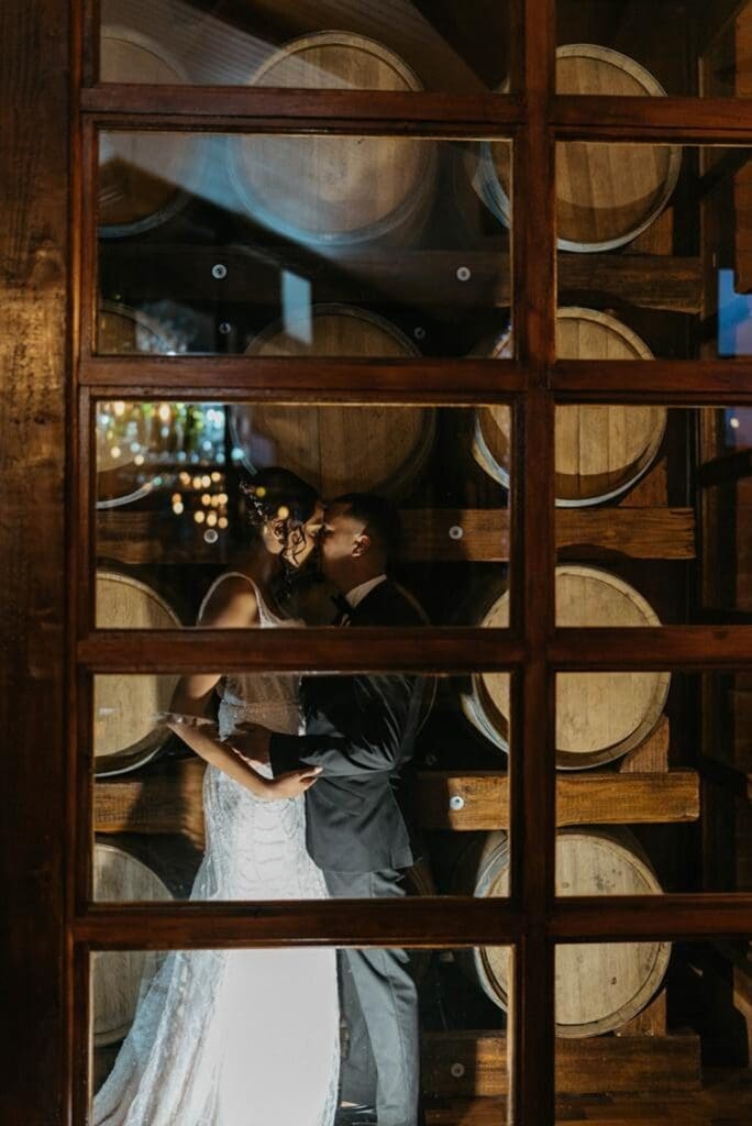 Bride and groom kissing in wine cellar