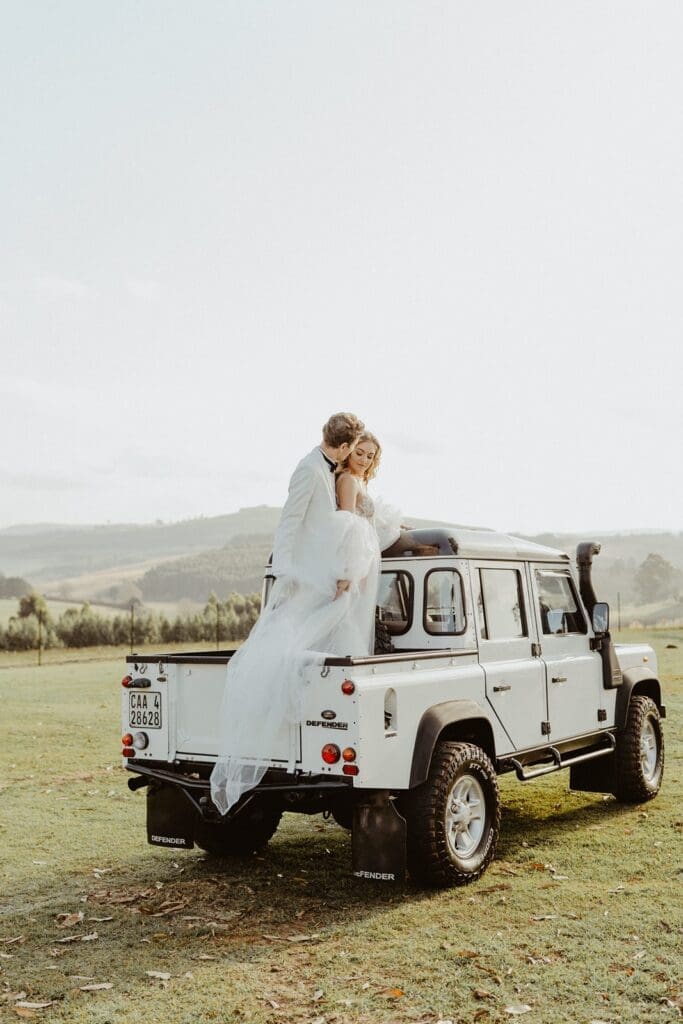 Bride and groom standing on old Defender