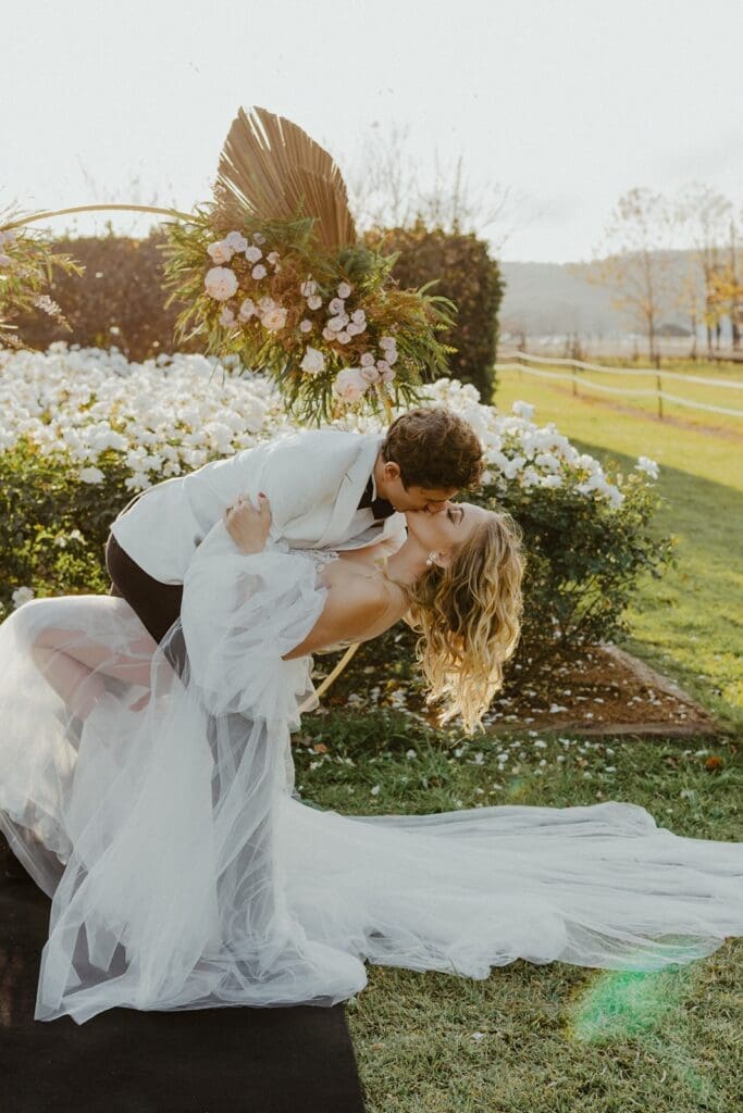 Groom dipping bride for a kiss on lawn at Highgate Wine Estate