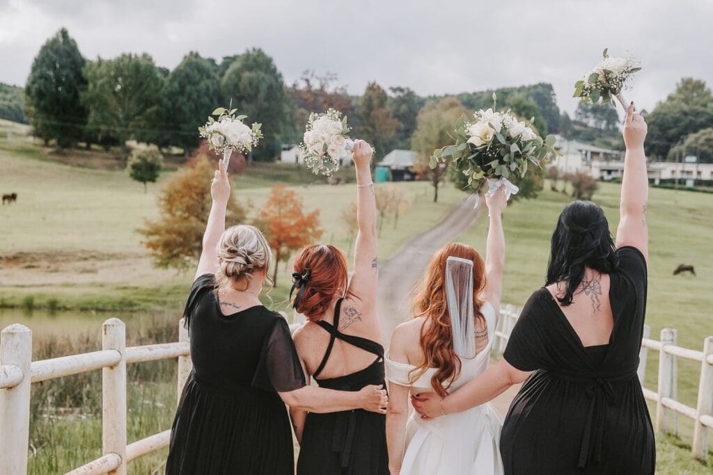 Bride and bridesmaids with backs to camera holding bouquets in the air