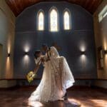 Bride being dipped by groom in glowing light in the chapel at Glen Eden