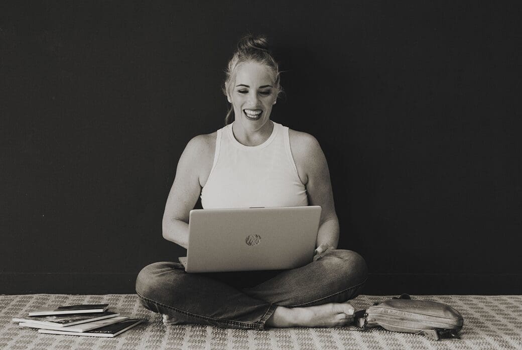 Woman sitting cross legged on floor with laptop on lap