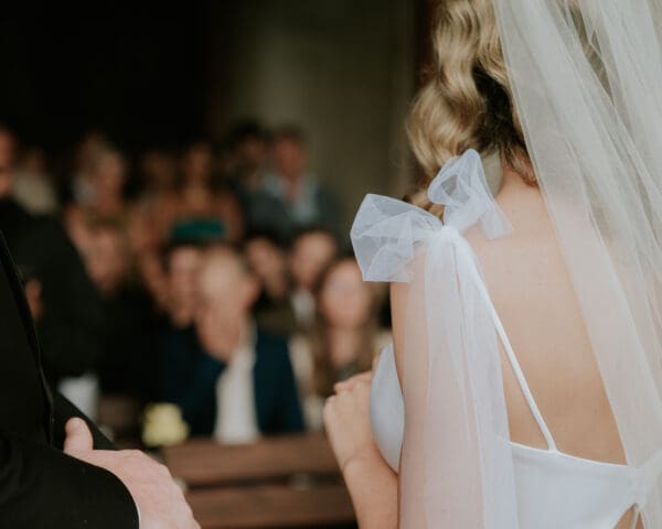 Back of bride's shoulder showing subtle bow on spaghetti strap and veil
