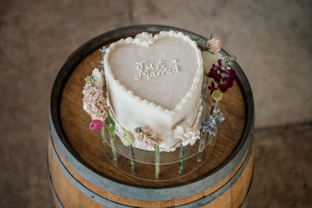Single tiered heart shaped wedding cake on wine barrel stand