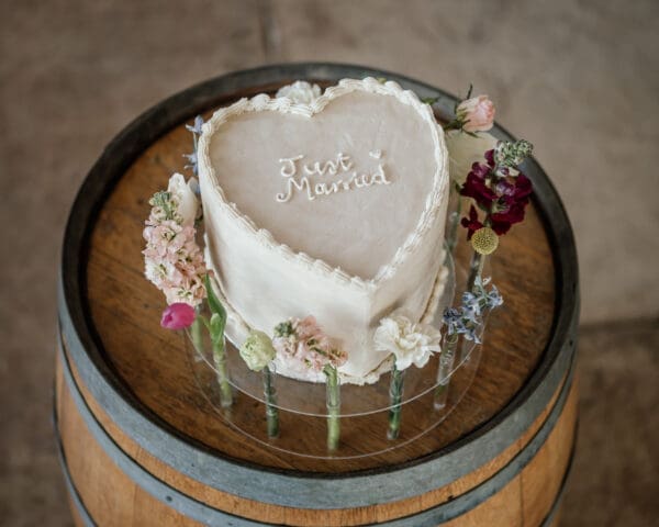 Single tiered heart shaped wedding cake on wine barrel stand