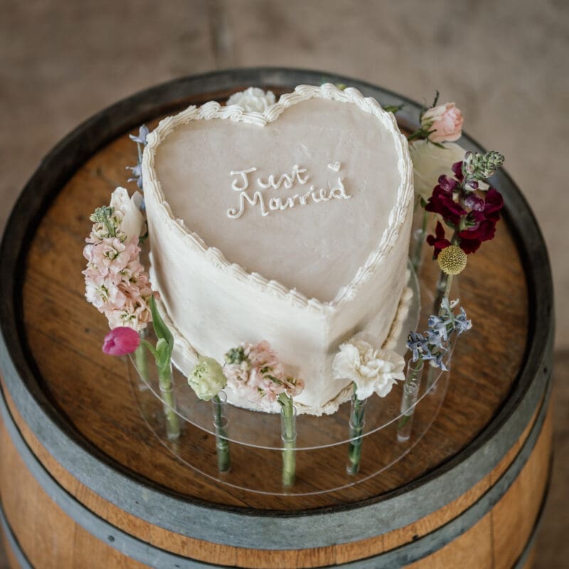 Single tiered heart shaped wedding cake on wine barrel stand