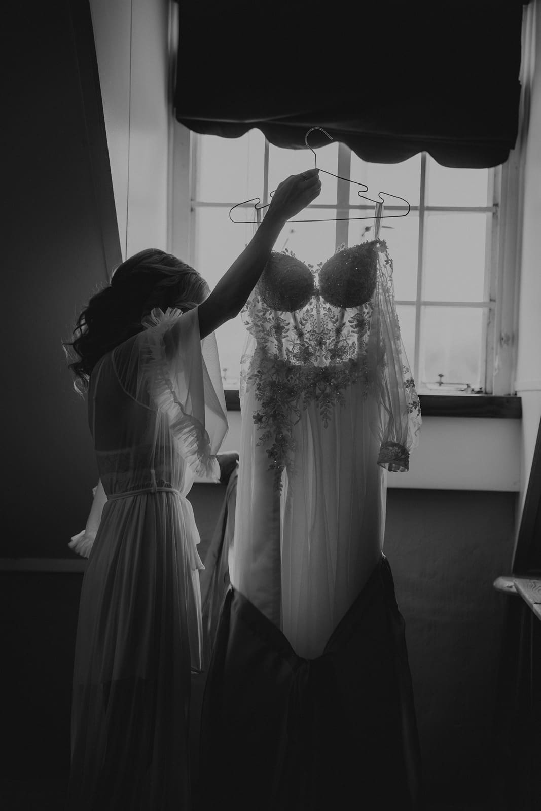 Black and white image of bride removing bridal gown from bag